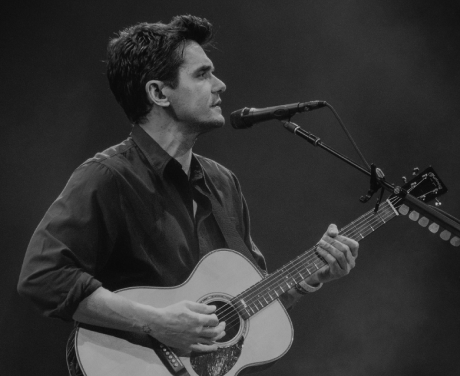 John Mayer playing an acoustic guitar on stage in Phoenix, Arizona in black and white.